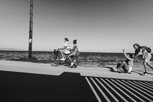 Photo of teenage girls hanging out together, cycling and skateboarding, and enjoying their summer break.