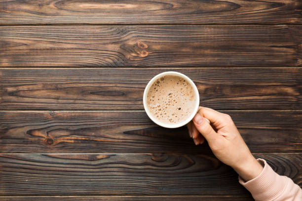 minimalistic style woman hand holding a cup of coffee on colored background. flat lay, top view cappuccino cup. empty place for text, copy space. coffee addiction. top view, flat lay - espresso women cup drink imagens e fotografias de stock