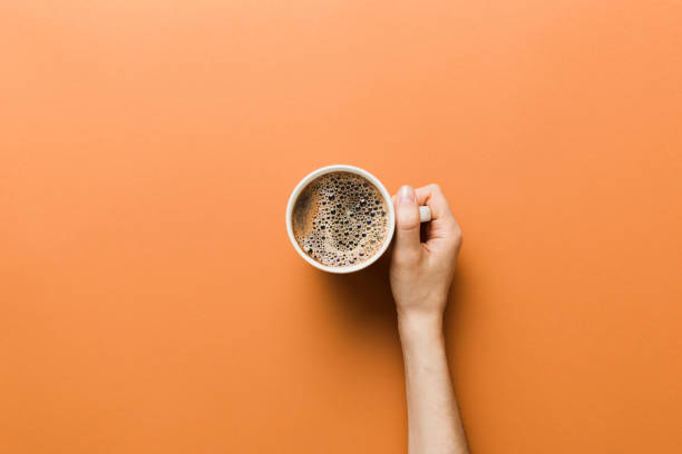 minimalistischer stil frau hand hält eine tasse kaffee auf farbigem hintergrund. flach gelegt, draufsicht cappuccino-tasse. leerer platz für text, kopierplatz. kaffeesucht. draufsicht, flache verlegung - kaffee stock-fotos und bilder