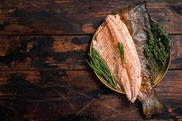 Photo of Baked Trout fillet, roasted fish on a plate with thyme and rosemary. Wooden background. Top view. Free space for your text