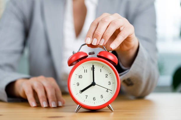istock Time to work. Business woman's hand touching the red alarm clock while sitting at her office desk. Concept of time management 1450271929