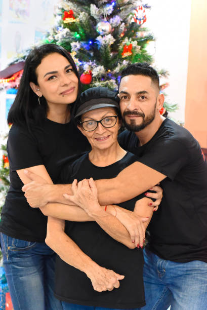 Mexican family standing together against christmas tree stock photo