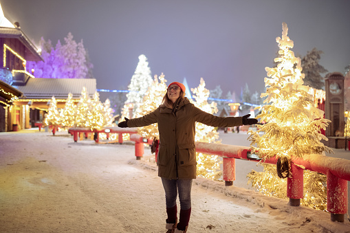 A smiling woman enjoys the magic of Santa's village during the holidays