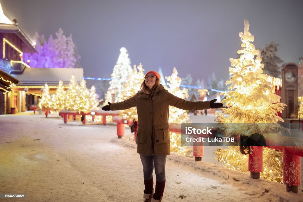 Female tourist visiting Santa Claus village A smiling woman enjoys the magic of Santa's village during the holidays Finland Stock Photo