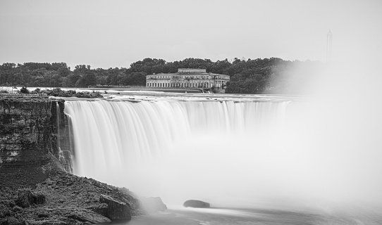 A grayscale of Niagara Falls and trees on the border of the USA and Canada