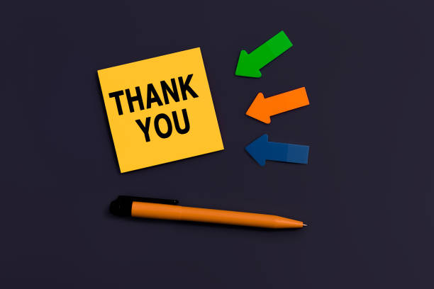 Thank you message on card for presentation, business. Orange square sticky note, near pen and colourful arrows on dark background, top view. Business concept. Home Office. Info concept mensaje de agradecimiento en la tarjeta para la presentación, negocio. nota adhesiva cuadrada naranja, bolígrafo cercano y flechas de colores sobre fondo oscuro, vista superior. concepto de negocio. oficina en casa. concepto de información