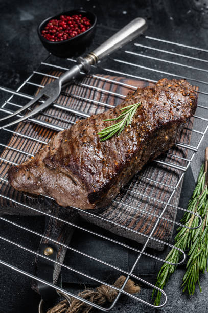 istock BBQ grilled tri tip beef steak on a grill. Black background. Top view 1450278671