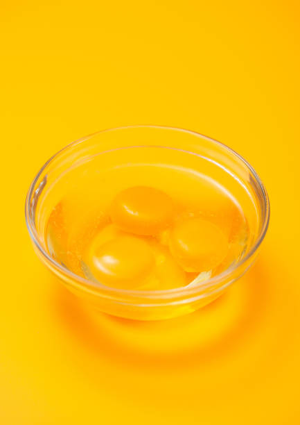istock Three egg yolks in bowl plate on yellow table background. 1450279730