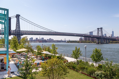 New York City, United States – August 20, 2019: View of the Williamsburg Bridge and lower Manhattan skyline from Domino Park in Williamsburg.