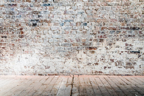 istock Weathered and distressed brick wall in a warehouse with wooden floor 1450283658