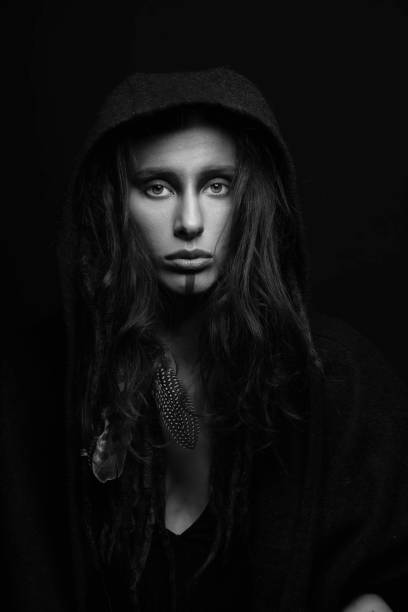 istock Model with make-up, dreadlocks, feather attached to her hair hiding under hood studio portrait 1450285340