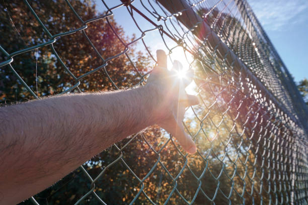 istock man hand grabbing metallic fence, feeling free 1450285356