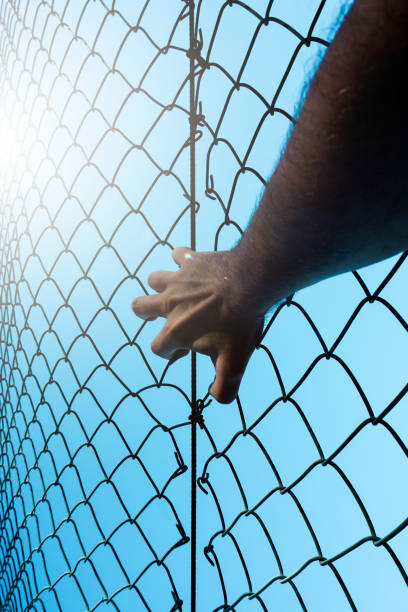 istock man hand grabbing metallic fence, feeling free 1450285360