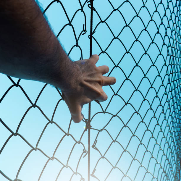 istock man hand grabbing metallic fence, feeling free 1450285361