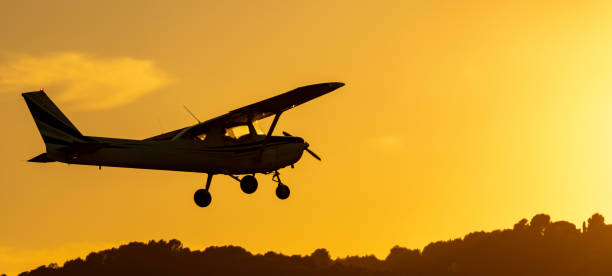 istock Silhouette of small propeller plane landing or taking off on the runway backlit under a yellow sun with the mountain below at sunset in Sabadell airport. 1450285429