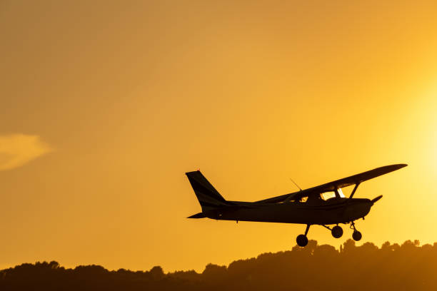 istock Silhouette of small propeller plane landing or taking off on the runway backlit under a yellow sun with the mountain below at sunset in Sabadell airport. 1450285440
