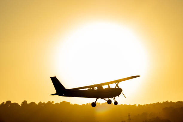 istock Silhouette of a small propeller plane landing or taking off on the runway backlit under a yellow sun at sunset at Sabadell airport. 1450285460