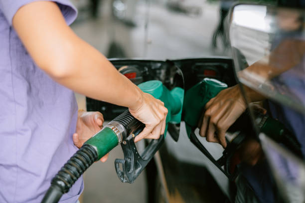 женщина заправляет машину на заправке - gas fuel pump labeling fuel and power generation стоковые фото и изображения