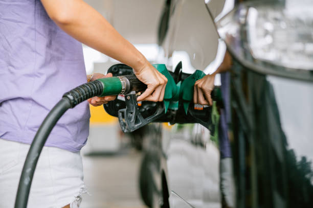 женщина заправляет машину на заправке - gas fuel pump labeling fuel and power generation стоковые фото и изображения