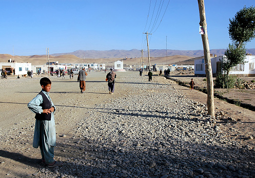 Chaghcharan, Ghor Province / Afghanistan: The main street in Chaghcharan one of the largest towns in a remote part of Central Afghanistan. Local life scene with a young man standing in the road.
