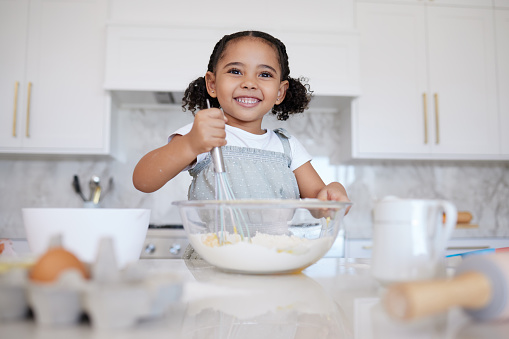 Happy girl kids baking in kitchen, house and home for childhood fun, learning and development. Smile young toddler child, little cooking chef and mixing bowl, sweets dessert, cookies and cake flour