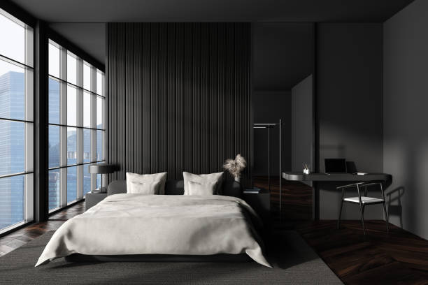 istock Front view on dark bedroom interior with bed, desk, laptop 1450294719