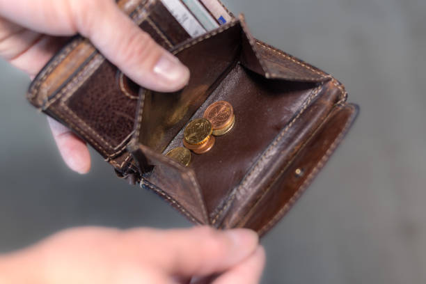 istock Man holding a wallet with a few coins in his hand 1450295949