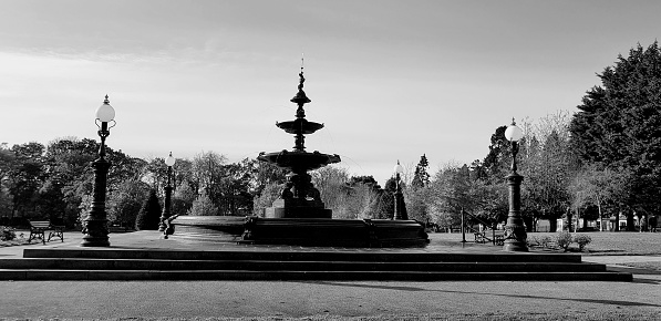 A grayscale shot of park with a large fountain