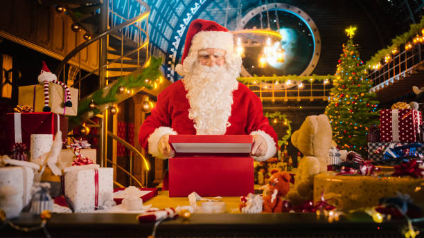 santa claus en su taller de estudio: envolver y empacar regalos de navidad para todos los niños buenos que se entregarán en la víspera de año nuevo. ofrece el regalo de la felicidad y la alegría a los niños emocionados - workshop santa claus christmas north pole fotografías e imágenes de stock