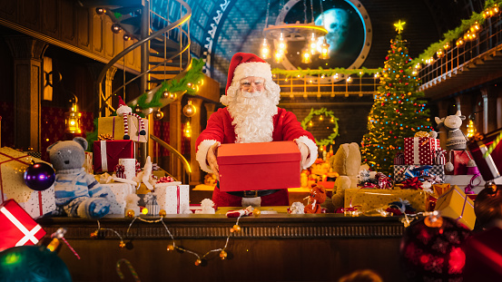Santa Claus in His Studio Workshop: Wrapping and Packing Christmas Gifts for all the Good Children to be Delivered on the Magical New Year Eve. He Offers the Gift of Happiness and Joy to Kids