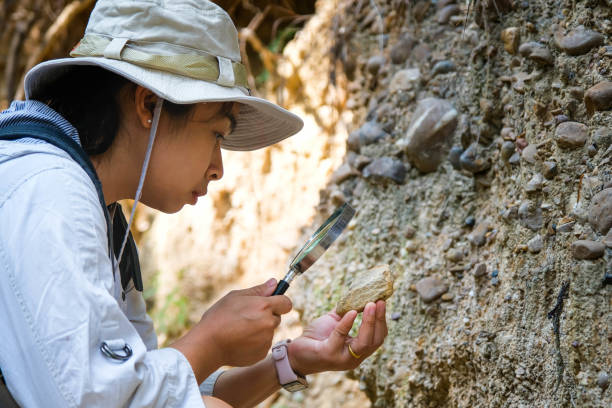 istock Female geologist using a magnifying glass examines nature, analyzing rocks or pebbles. Researchers collect samples of biological materials. Environmental and ecology research. 1450303839