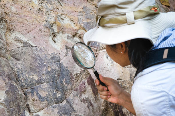 istock Female geologist using a magnifying glass examines nature, analyzing rocks or pebbles. Researchers collect samples of biological materials. Environmental and ecology research. 1450303868