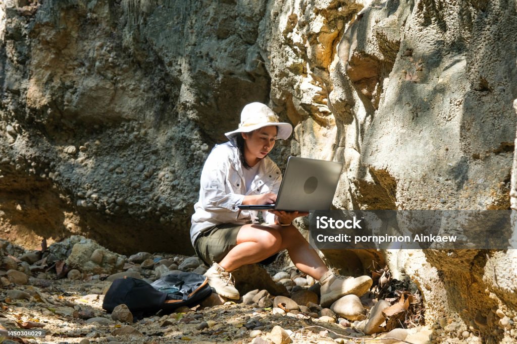 Female geologist using laptop computer examining nature, analyzing rocks or pebbles. Researchers collect samples of biological materials. Environmental and ecology research. Geologist Stock Photo