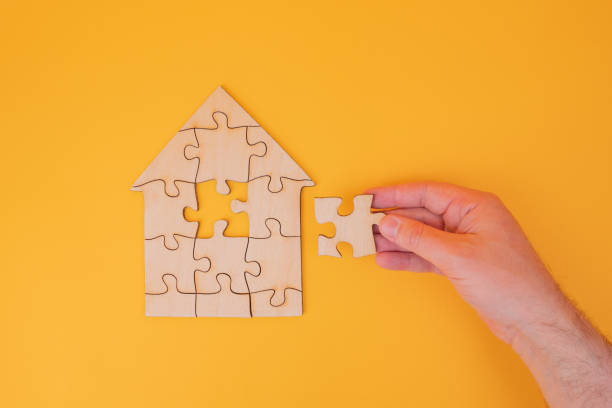 istock Puzzle house with a missing piece in mans hand. The acquisition or construction comfortable dream home. Mortgage loan purchase real estate. Arrangement premises repair. Availability and cheapness. Finish building 1450305518