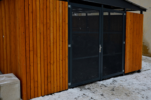 garage with wooden paneling and transparent mesh door. bin storage near the boarding house. protects citizens' property and order in the closed shelter. car parking safe and without snow, slats, net