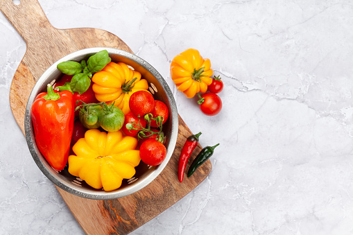 Various colorful garden tomatoes and bell peppers. Fresh vegetables and spices. Top view flat lay with copy space