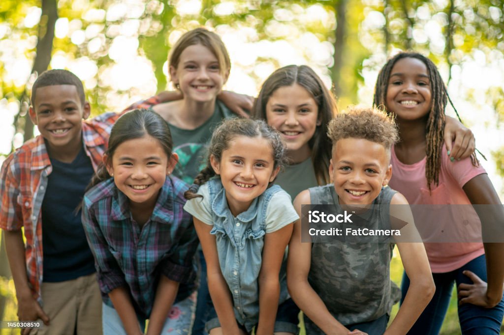 Children Outside A large group of school aged children huddle together outside for a portrait.  They are each dressed casually and are laughing and smiling as they enjoy each others company. Child Stock Photo