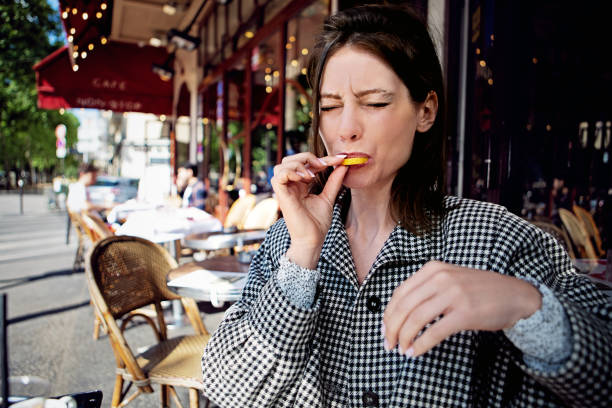porträt einer frau, die in einem café eine zitronenscheibe isst - humor human face women grimacing stock-fotos und bilder