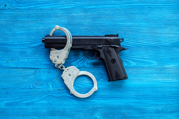 istock Crime concept. Hand gun weapon with handcuffs 1450310595