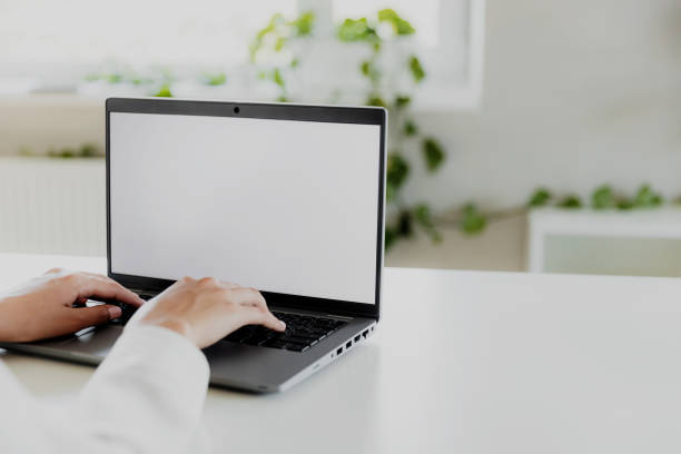istock Woman hands typing on the laptop with blank white screen mockup laying on table 1450315974