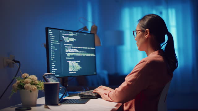 Young Asian woman software developers using computer to write code sitting at desk