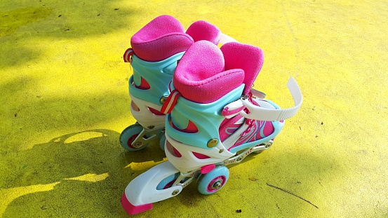 Colorful inline skates for girl on the yellow floor