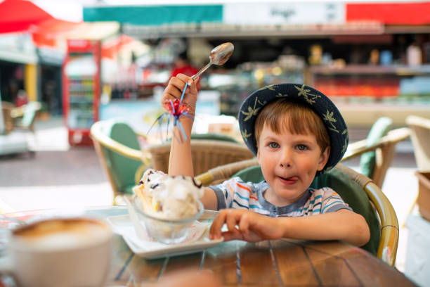 istock Cute little boy eats ice-cream in a cafe 1450324161