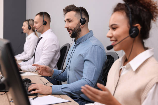 istock Call center operators working in modern office, focus on man with headset 1450324973