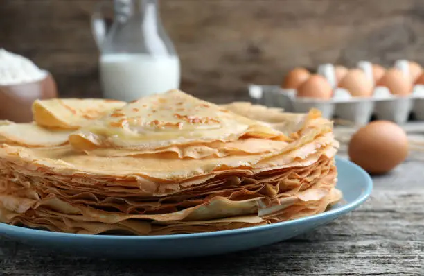 Stack of delicious crepes on wooden table, closeup