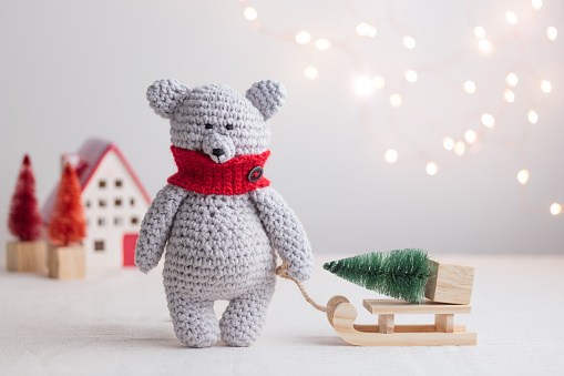 Crocheted white bear with the Christmas tree on the wooden sled Horizontal