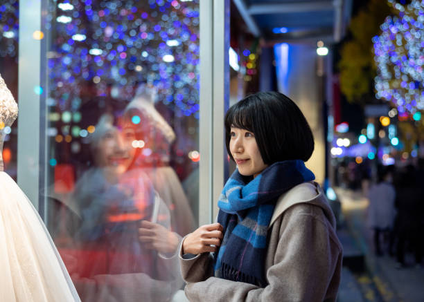 クリスマスの夜にウィンドウショッピングをする若い女性
