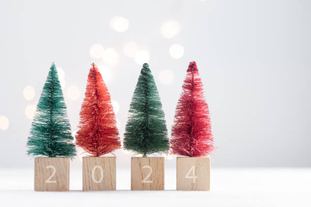 istock Cute Christmas miniature fir trees on a white table with bokeh lights 1450330078