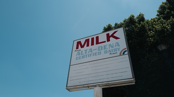 Los Angeles, United States – June 15, 2022: The Old Milk advertising billboard LA under green trees and blue sky