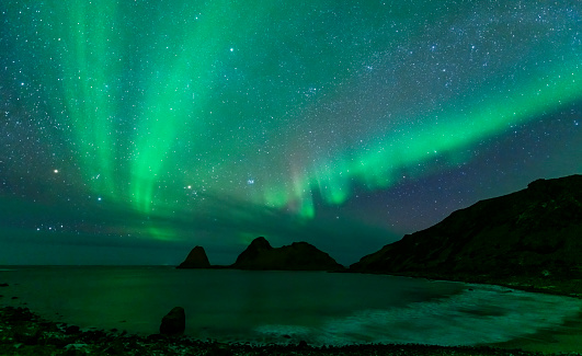 Northern landscape. Winter background with green Aurora Borealis and stars trails